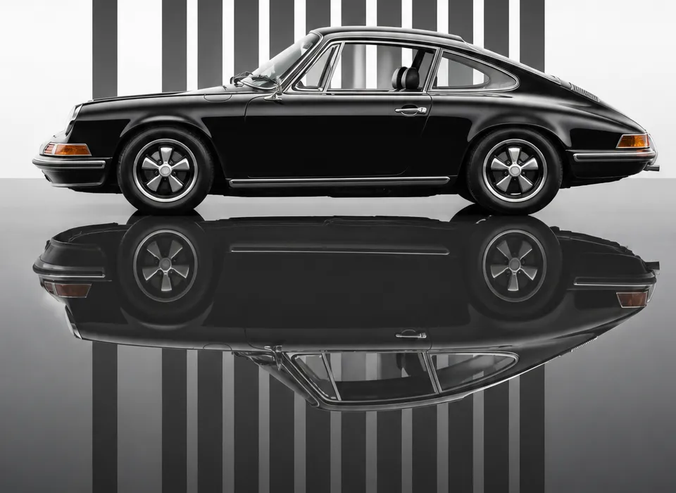 A black classic sports car photographed side-on against a studio backdrop